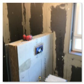 Die Wände sind mit Gipsplatten verkleidet, während eine Toilette und Werkzeuge auf dem Boden für Bauarbeiten bereitstehen.