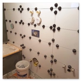 Der Fortschritt einer Fliesenverlegung zeigt eine fast fertige Wand mit verschiedenen Installationen und Werkzeugen im Raum.