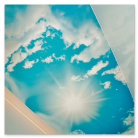 Ein strahlend blauer Himmel mit weißen Wolken und einer hellen Sonne, die durch die Wolken scheint.