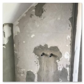 Die Wand zeigt ungleichmäßigen Putz und zwei Rohre, die aus der Oberfläche herausragen, in einem renovierungsbedürftigen Raum.
