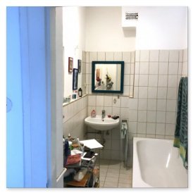 Ein kleines Badezimmer mit einer Badewanne, einem Waschbecken und einem Spiegel, der die Wand reflektiert.