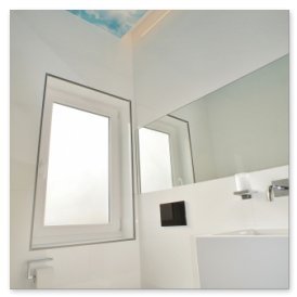 Ein modernes Badezimmer mit einem großen Fenster, das Tageslicht hereinlässt, und einem eleganten Spiegel an der Wand.