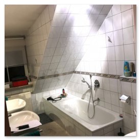Ein modernes Badezimmer mit schrägen Wänden, einer Badewanne und zwei Waschbecken, die ordentlich angeordnet sind.