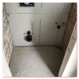 Der Innenraum zeigt eine vorbereitete Dusche mit Aquapanel und sichtbaren Wasseranschlüssen an der Wand.