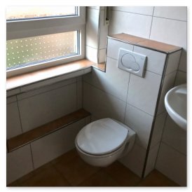 Das Bild zeigt ein helles Badezimmer mit Fliesen, einem WC in der Ecke und einem Holzregal unter dem Fenster.