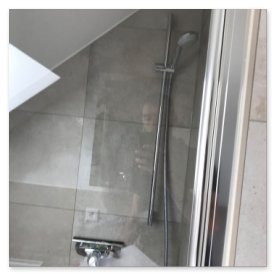 Der Blick auf eine stilvolle Duschkabine, die mit hellen Fliesen und einem minimalistischen Duscharmatur ausgestattet ist.