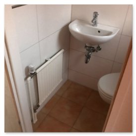 Der Raum zeigt ein kompaktes WC mit einem modernen Waschbecken und einer weißen Heizung, umgeben von hellen Fliesen.